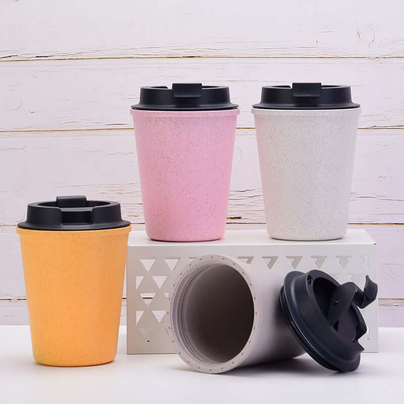 Yellow wheat straw coffee cup with two pink and white cups showcasing eco-friendly, double-layer design for hot or cold beverages.